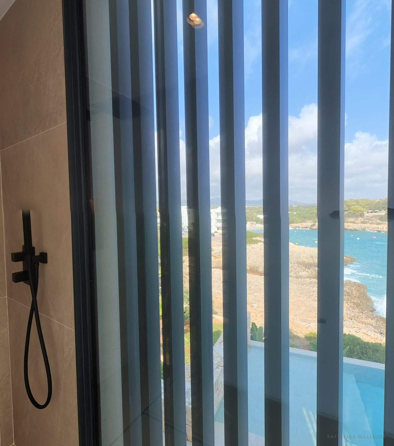 Bad mit Lamellenfenster und Blick aufs Meer