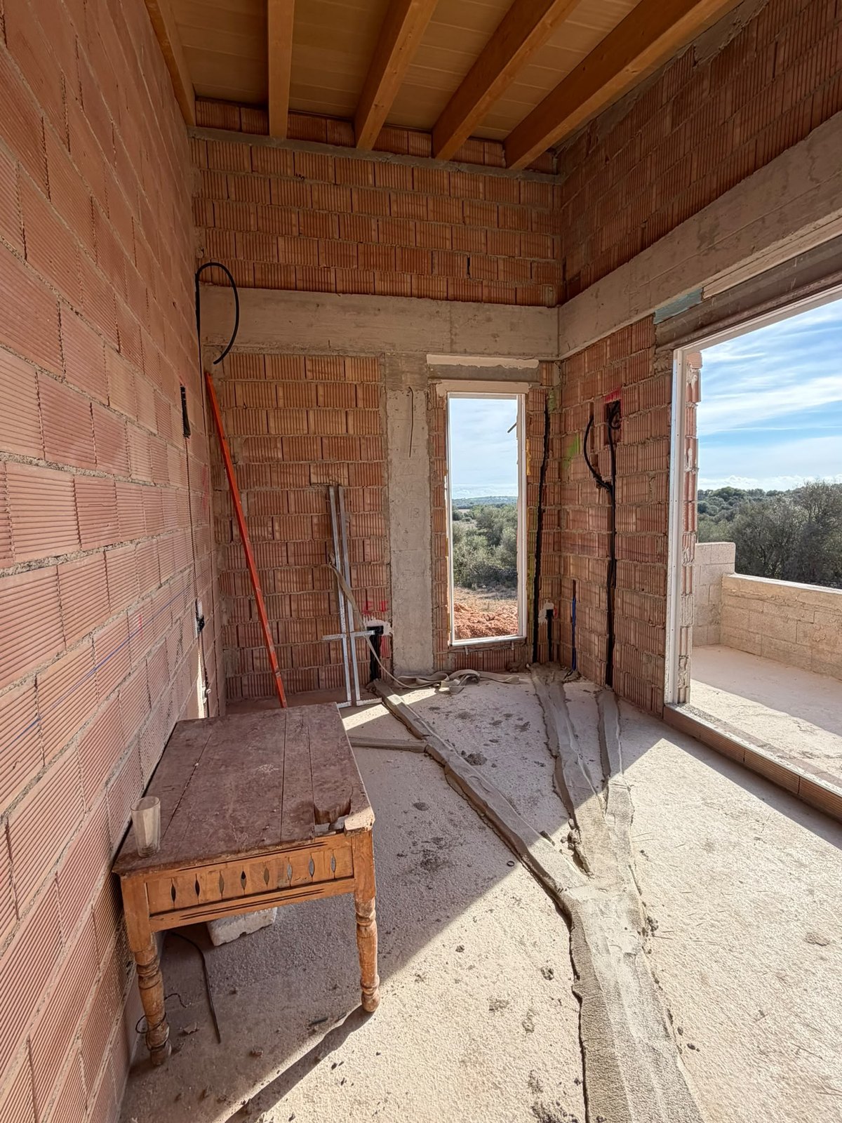 Raum unter der Holzbalkendecke mit verlegten Leerrohren und Terrassenöffnung, Oktober 2026