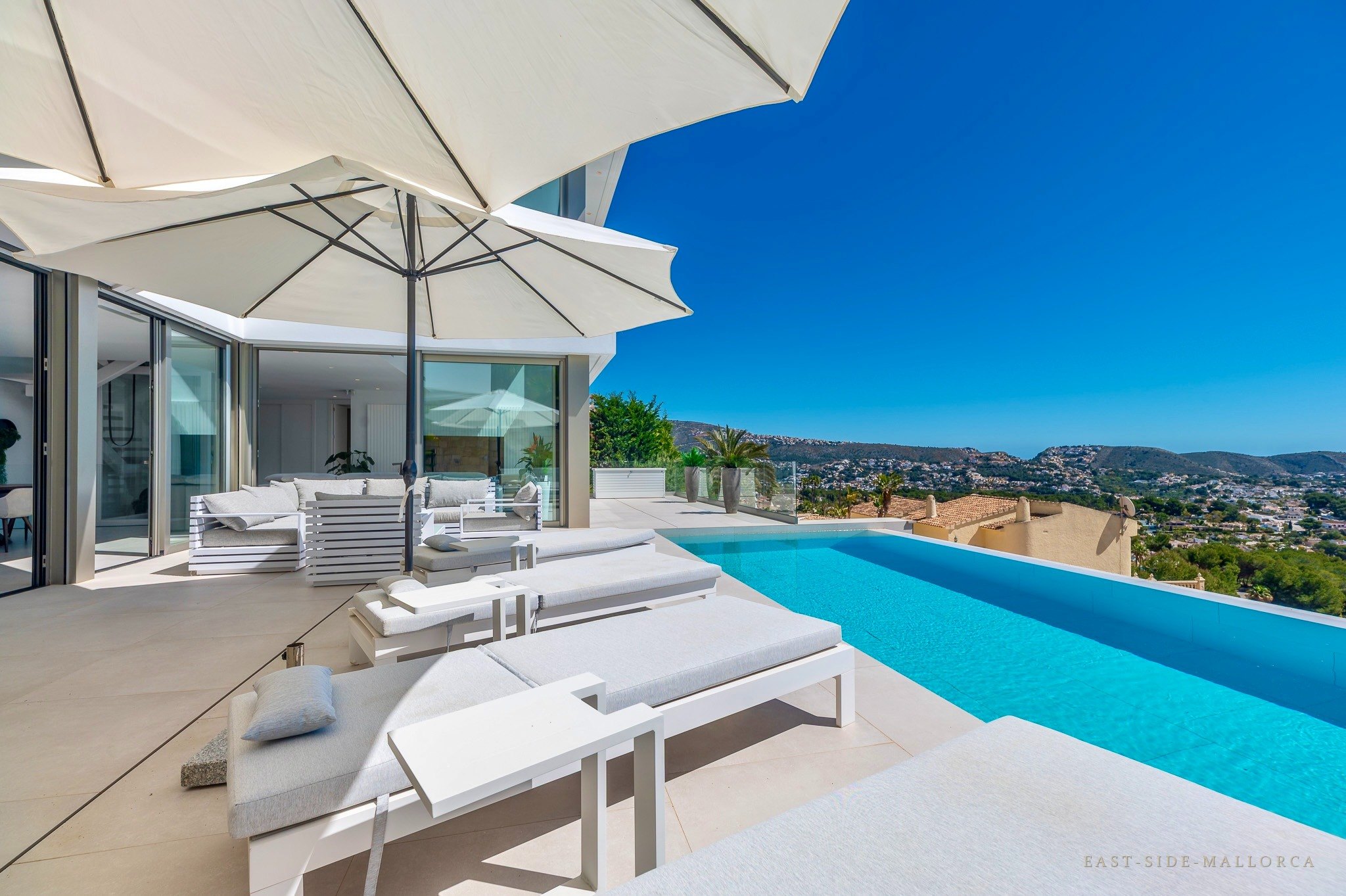Beheizter Infinity-Pool mit Sonnenliegen und Blick über die Bucht von Moraira