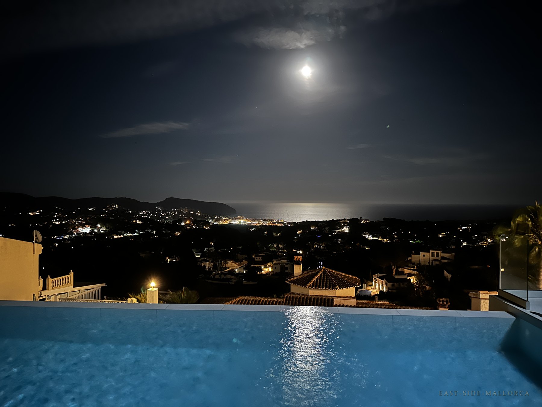 Infinity-Pool bei Nacht mit Vollmond über der Bucht von Moraira