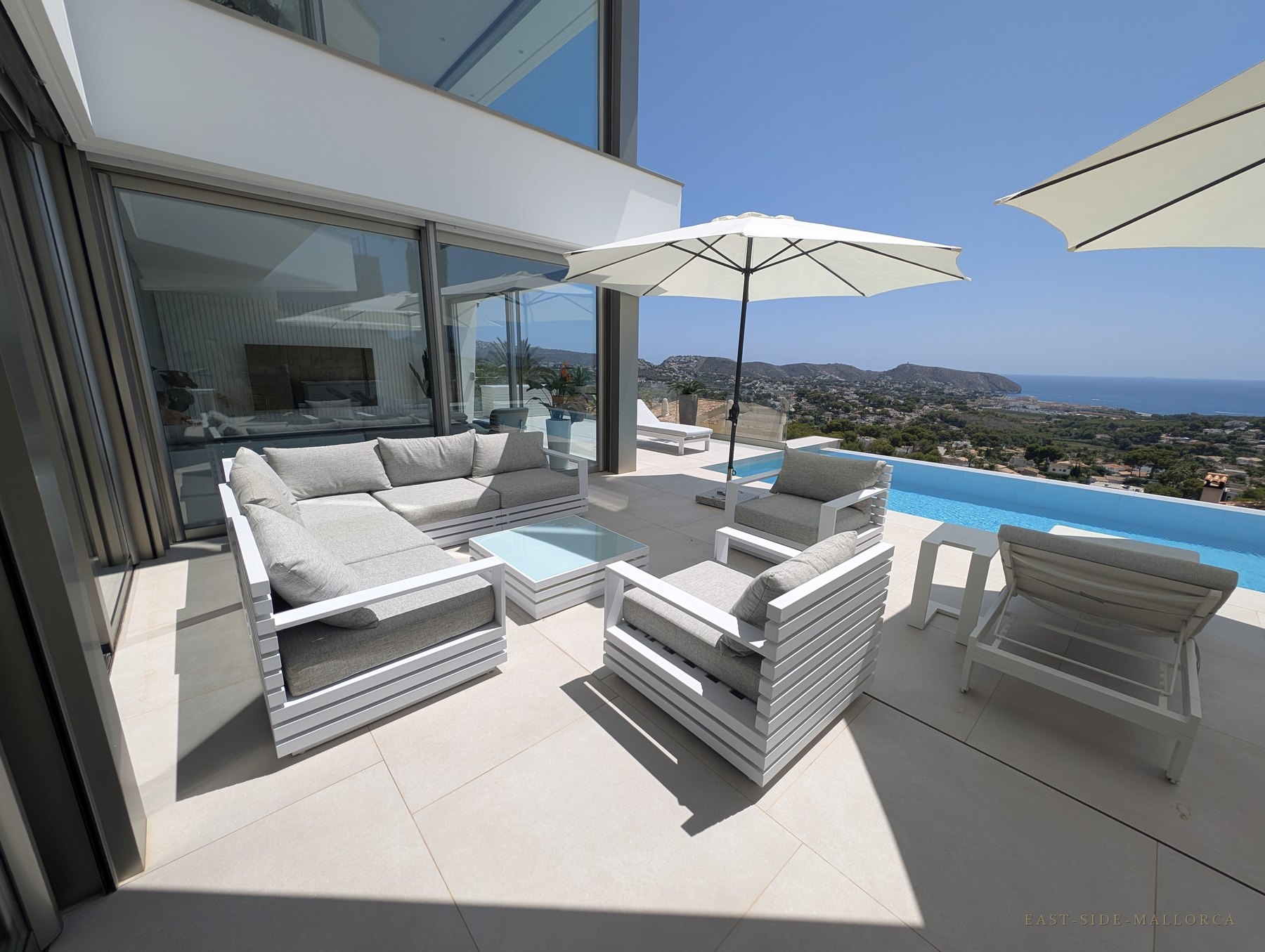 Überdachte Terrassen-Lounge mit Sitzgruppe, Glas-Wohnzimmer und Infinity-Pool